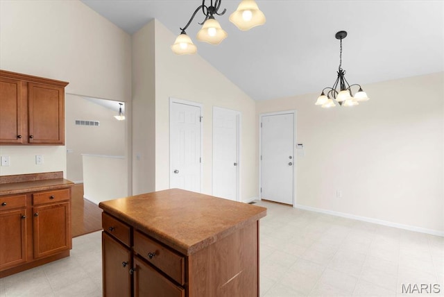 724 E Wesley Dr, Ofallon, IL 62269 - kitchen with a chandelier, vaulted ceiling, light floors, brown cabinets, and a center island