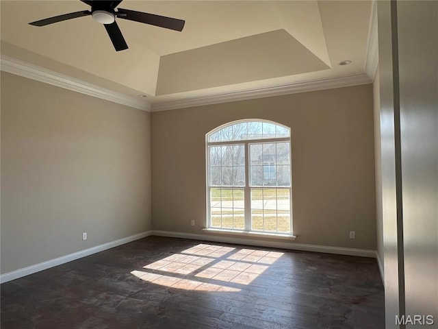 spare room with crown molding, baseboards, a ceiling fan, and a tray ceiling