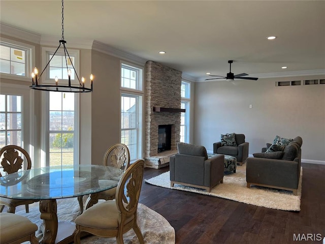 dining room featuring crown molding, dark wood finished floors, recessed lighting, a ceiling fan, and a stone fireplace