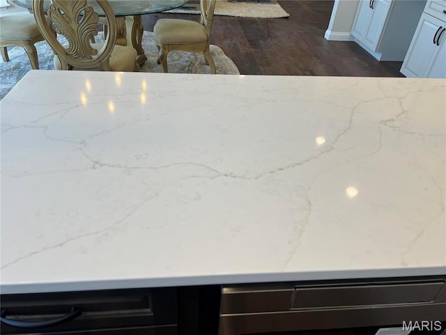 detailed view of light stone counters and dark wood finished floors