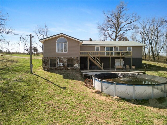 rear view of house featuring stairs, a deck, stone siding, a yard, and a chimney