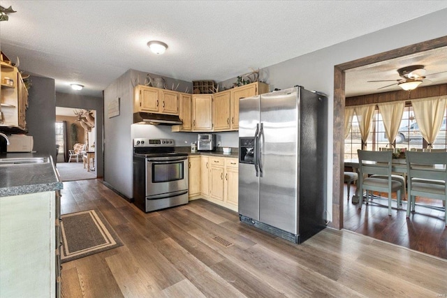 kitchen with appliances with stainless steel finishes, under cabinet range hood, a sink, dark wood-type flooring, and a textured ceiling