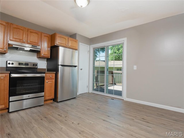 1464 Monopoly Dr, Florissant, MO 63031 - kitchen with stainless steel appliances, under cabinet range hood, light wood-style floors, tasteful backsplash, and dark countertops