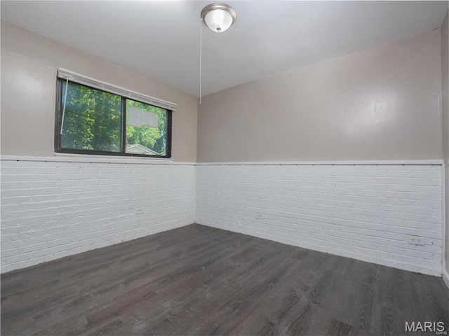 1464 Monopoly Dr, Florissant, MO 63031 - empty room featuring brick wall, dark wood-style floors, and wainscoting