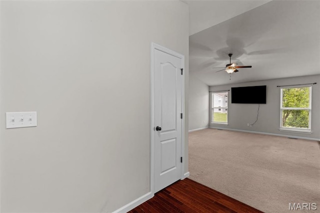 empty room with baseboards, a ceiling fan, dark wood-style floors, and dark colored carpet