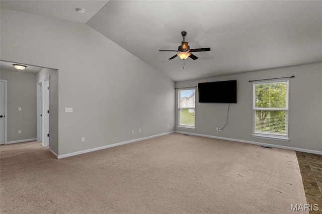 carpeted empty room with vaulted ceiling, a ceiling fan, and baseboards