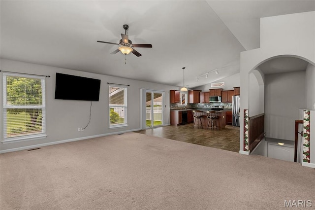 carpeted living area with a ceiling fan, healthy amount of natural light, rail lighting, baseboards, and lofted ceiling