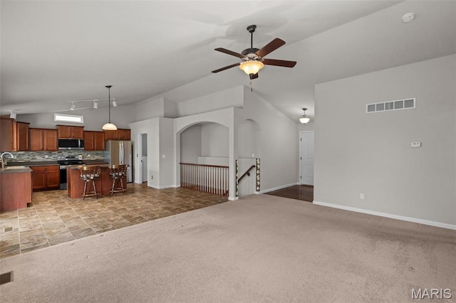 living room with vaulted ceiling, light carpet, a ceiling fan, and baseboards