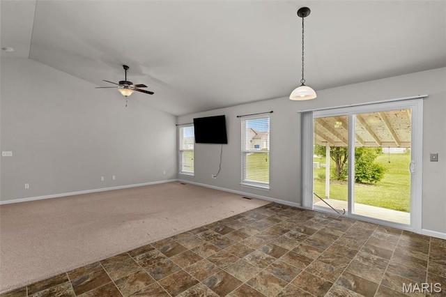 empty room with stone finish floors, lofted ceiling, baseboards, a ceiling fan, and dark colored carpet