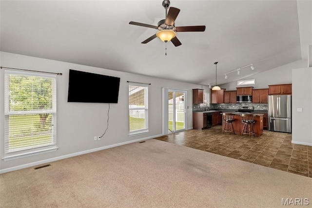 carpeted living area featuring vaulted ceiling, baseboards, a ceiling fan, rail lighting, and a sink