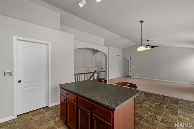 kitchen featuring dark brown cabinets, ceiling fan, arched walkways, dark countertops, and lofted ceiling