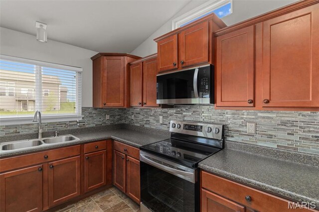 kitchen with appliances with stainless steel finishes, a sink, dark countertops, backsplash, and vaulted ceiling