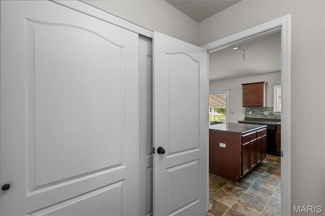 kitchen featuring dark countertops, stone finish flooring, and backsplash