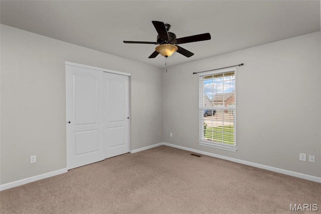 unfurnished bedroom with carpet flooring, baseboards, a closet, and ceiling fan