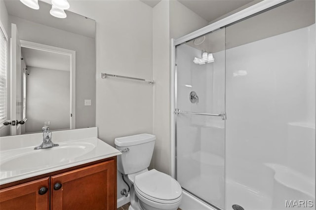 bathroom with a shower stall, toilet, and vanity