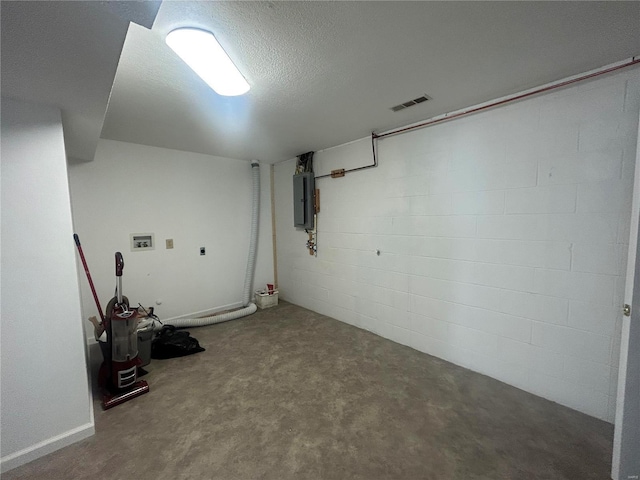 finished basement with electric panel, a textured ceiling, and concrete block wall