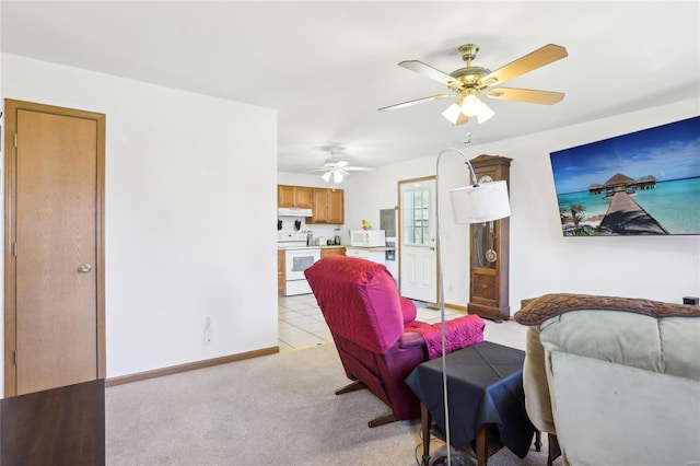 living room featuring baseboards, a ceiling fan, and light carpet