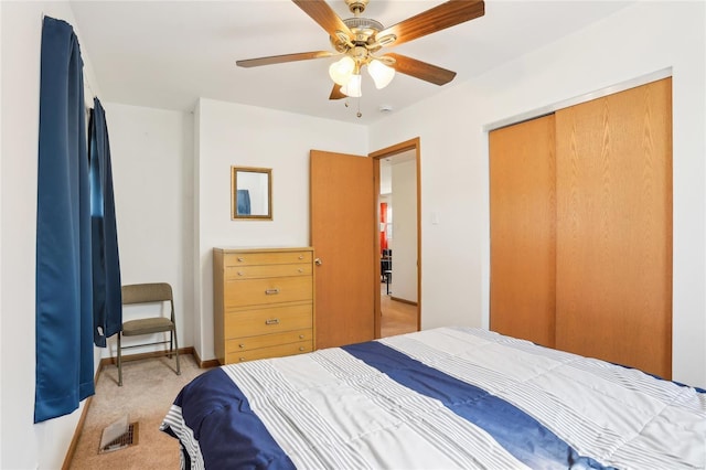 bedroom featuring light colored carpet, a closet, baseboards, and a ceiling fan