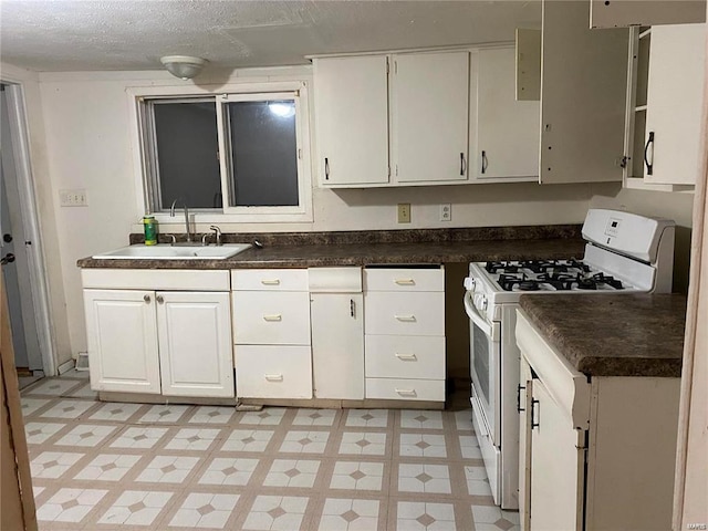 123 S Main St, Witt, IL 62094 - kitchen with a sink, white gas range, white cabinets, dark countertops, and a textured ceiling