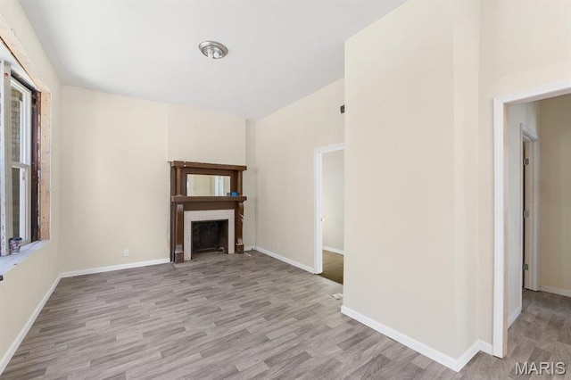 4 Lewis Pl, Saint Louis, MO 63113 - unfurnished living room with wood finished floors, a brick fireplace, and baseboards