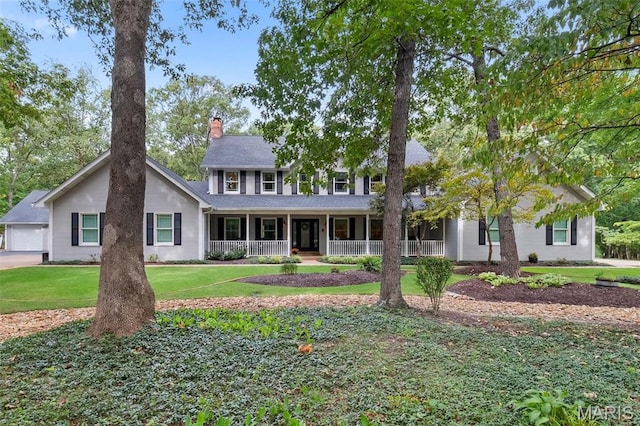 colonial inspired home featuring a porch, a chimney, and a front yard