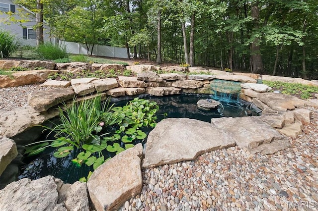 view of yard featuring a garden pond and fence