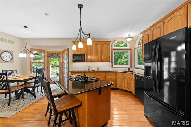 kitchen with black appliances, a sink, plenty of natural light, and light wood finished floors