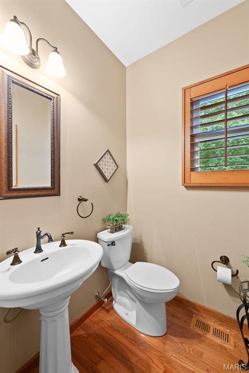 bathroom with wood finished floors, baseboards, and toilet