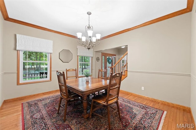 dining space with a chandelier, ornamental molding, baseboards, stairs, and wood finished floors