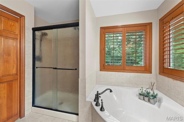bathroom featuring a stall shower, a bath, and tile patterned flooring
