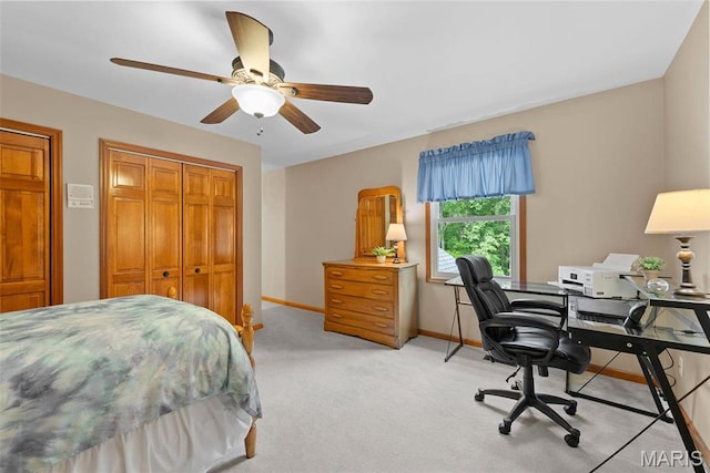 bedroom with baseboards, a closet, light carpet, a desk, and a ceiling fan