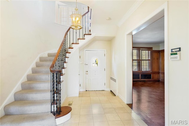 910 Kent Rd, Ladue, MO 63124 - foyer with stairs, a chandelier, radiator, ornamental molding, and tile patterned flooring