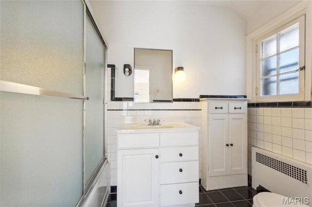 910 Kent Rd, Ladue, MO 63124 - full bath with tile walls, radiator heating unit, vanity, tile patterned flooring, and bath / shower combo with glass door