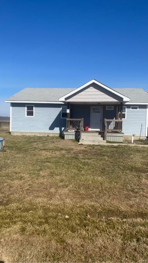 view of front of property with a front lawn, a porch, and roof with shingles