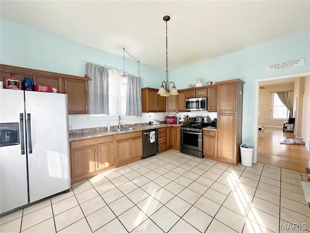 703 S Main St, Troy, IL 62294 - kitchen featuring stainless steel appliances, a sink, light tile patterned flooring, decorative light fixtures, and brown cabinets