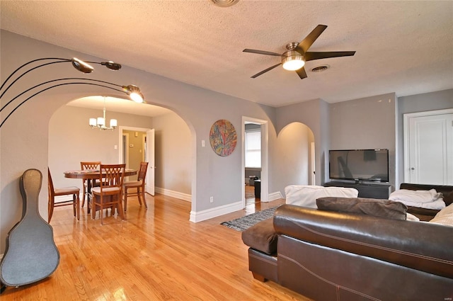 7227 Dartmouth Ave, Saint Louis, MO 63130 - living area with arched walkways, a textured ceiling, a chandelier, a ceiling fan, and light wood-type flooring