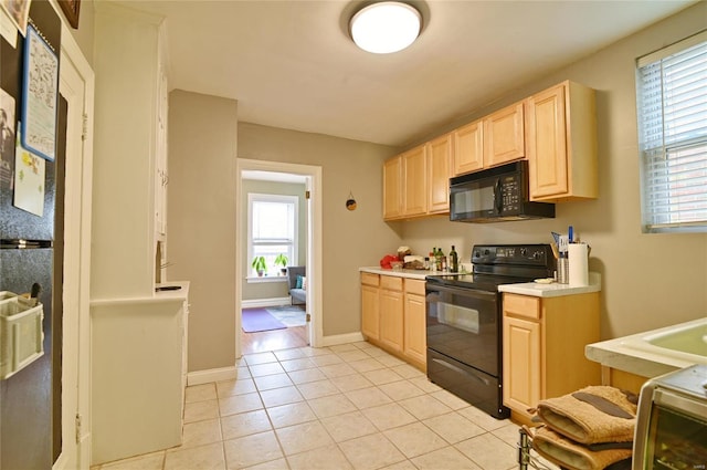 7227 Dartmouth Ave, Saint Louis, MO 63130 - kitchen featuring black appliances, light brown cabinetry, light countertops, light tile patterned floors, and baseboards