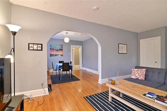 7227 Dartmouth Ave, Saint Louis, MO 63130 - living area with arched walkways, light wood finished floors, and baseboards