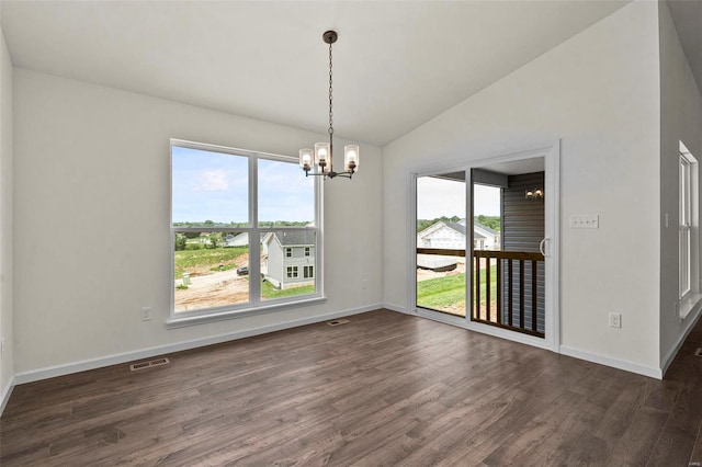 unfurnished dining area with vaulted ceiling, a chandelier, dark wood finished floors, and baseboards