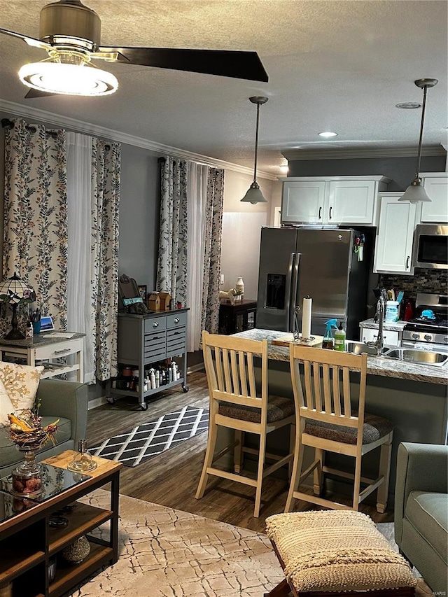 610 W Maple St, Advance, MO 63730 - kitchen featuring appliances with stainless steel finishes, ornamental molding, light wood-type flooring, white cabinets, and a breakfast bar area