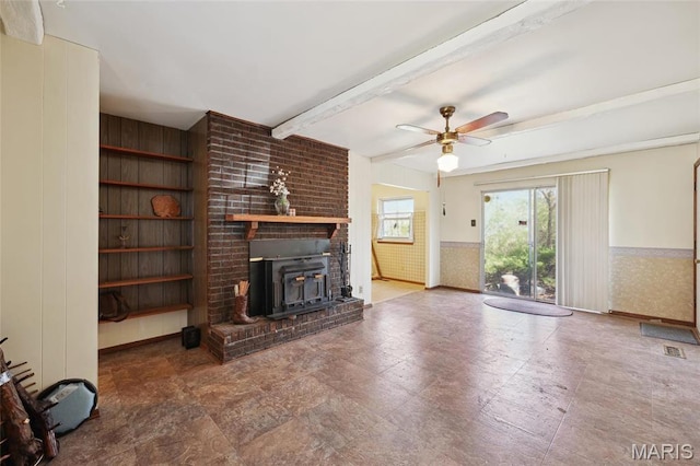 32 Oak Forest Dr, Saint Charles, MO 63303 - unfurnished living room featuring beam ceiling, wainscoting, a ceiling fan, a wood stove, and built in features