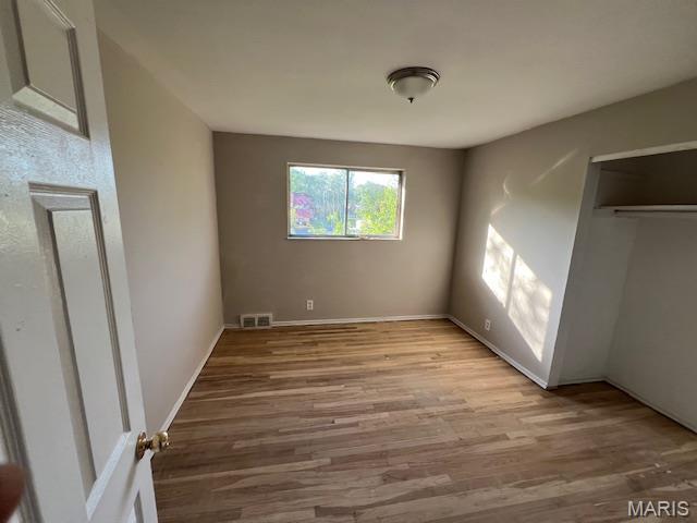 8440 N Broadway N, Saint Louis, MO 63147 - unfurnished bedroom featuring wood finished floors, baseboards, and a closet
