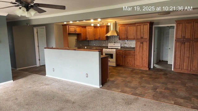 kitchen featuring white range with gas cooktop, wall chimney exhaust hood, crown molding, brown cabinetry, and a ceiling fan