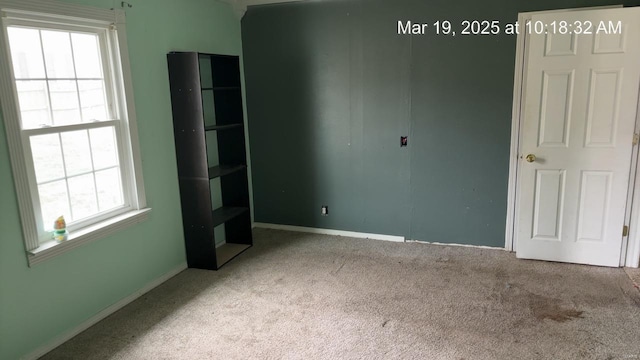 unfurnished room featuring carpet floors and baseboards