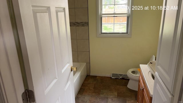 bathroom featuring toilet, vanity, baseboards, and stone finish floors