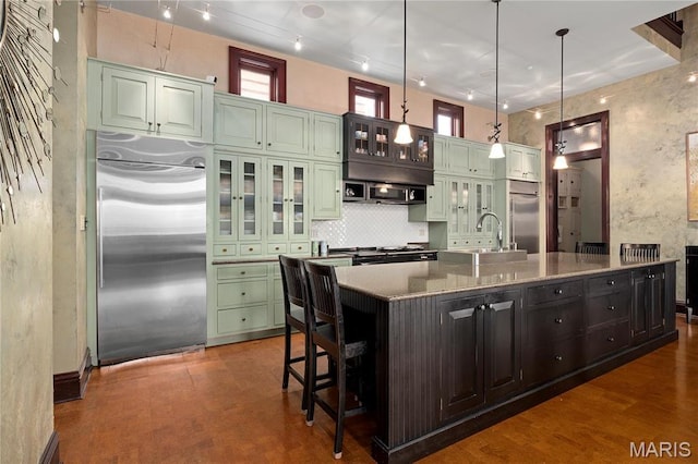3520 Galt House Dr, Saint Charles, MO 63301 - kitchen featuring appliances with stainless steel finishes, green cabinetry, a sink, backsplash, and an island with sink