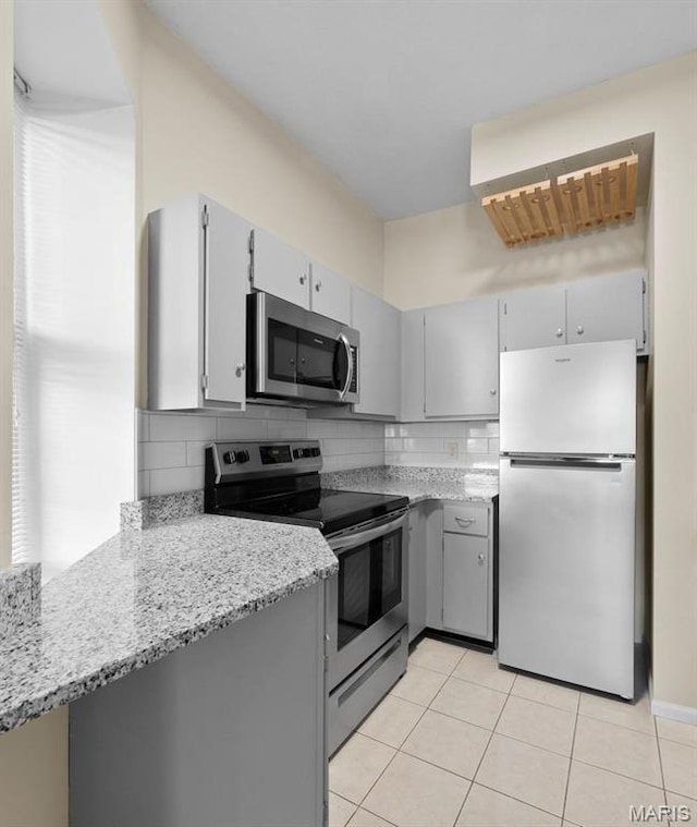 4319 Lindell Blvd Unit A, Saint Louis, MO 63108 - kitchen featuring appliances with stainless steel finishes, light tile patterned floors, gray cabinets, tasteful backsplash, and light stone counters