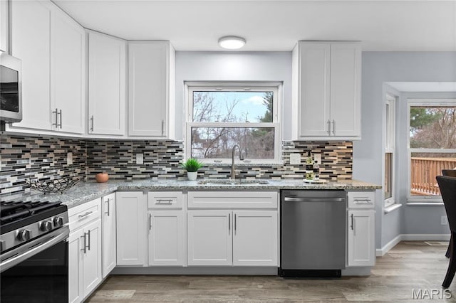 3524 Espace Ct, Florissant, MO 63034 - kitchen with stainless steel appliances, a sink, white cabinetry, and backsplash