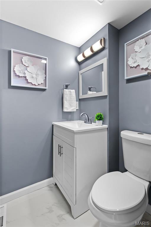 3524 Espace Ct, Florissant, MO 63034 - bathroom featuring vanity, marble look tiles, toilet, and baseboards