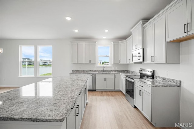 177 Arpent Aly, Saint Charles, MO 63301 - kitchen with appliances with stainless steel finishes, a kitchen island, light wood-style floors, light stone counters, and recessed lighting